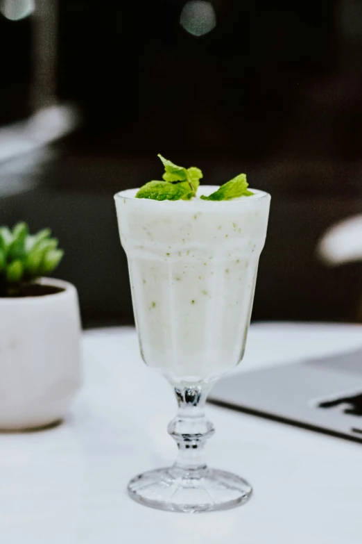 a white table topped with a glass filled with soing