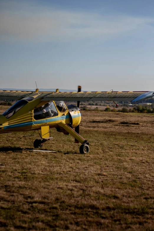 two small yellow airplanes are on the grass