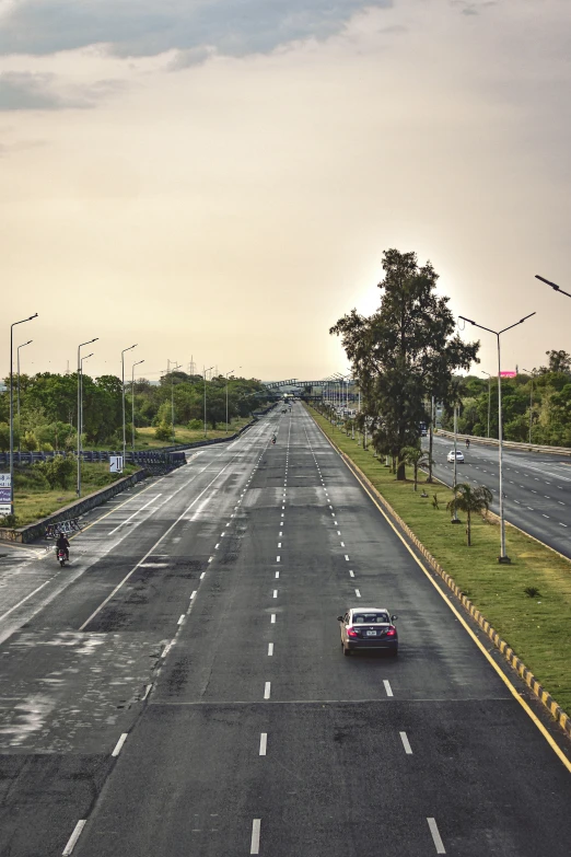 two cars drive down a paved highway near the forest