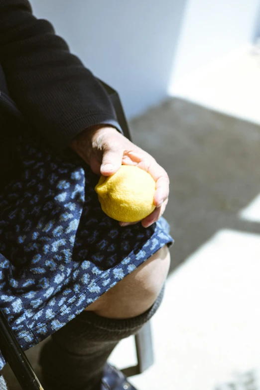 a person sitting down and holding a lemon