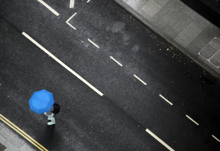 a person walks with a blue umbrella in the rain