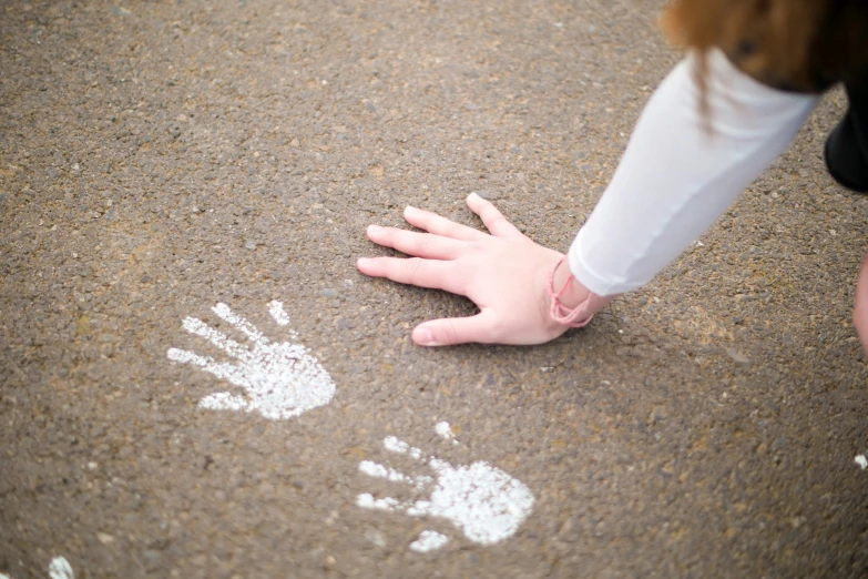 child's hand print on asphalt near adult hand