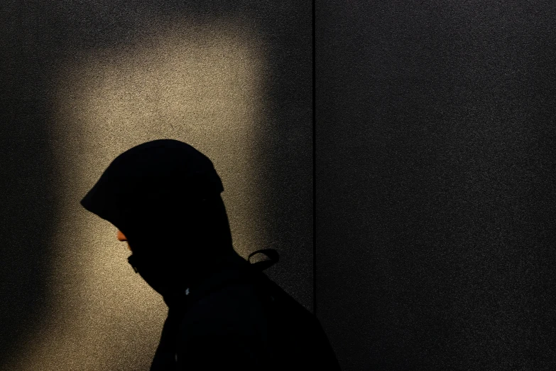 the silhouette of a person standing in front of a dark wall