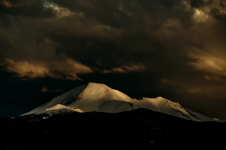 a big snow covered mountain sits in the distance under cloudy skies