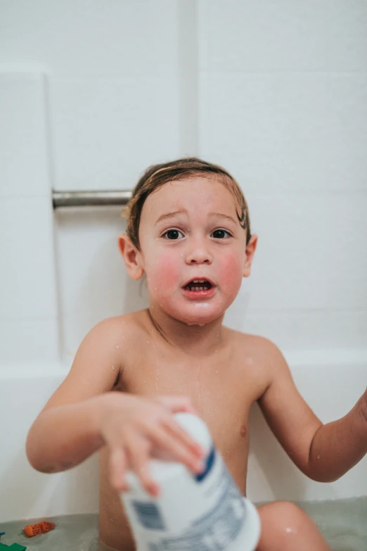 a small child is holding a bottle of liquid