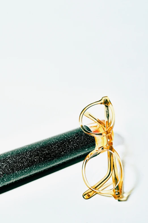 there is a pen, reading glasses and an object lying next to it