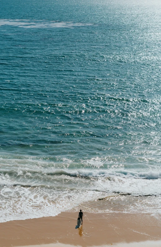 the lone man is walking along the sandy beach