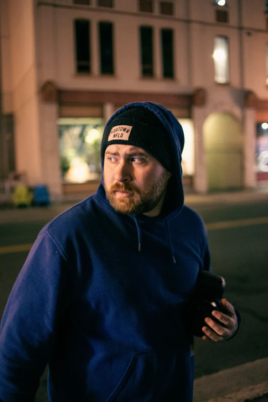 man in blue jacket walking on city street at night