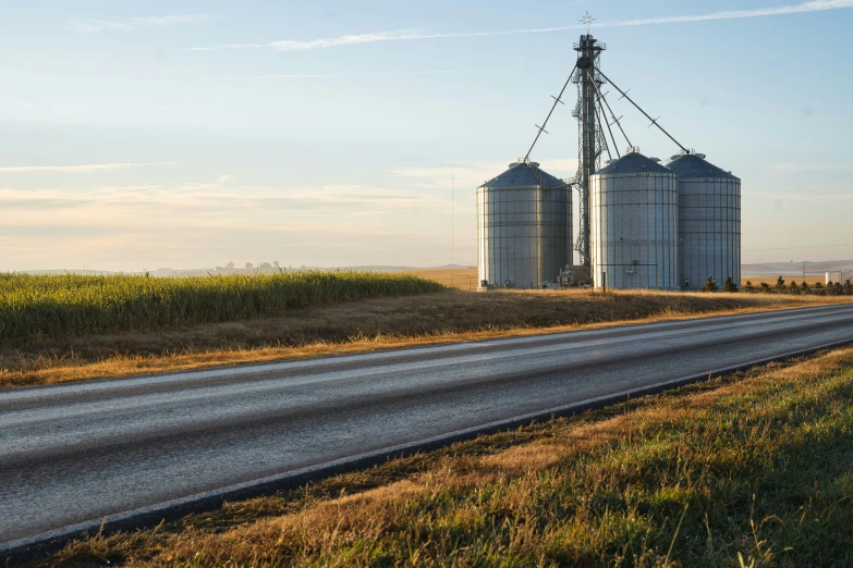 two large grain silos stand next to an empty road