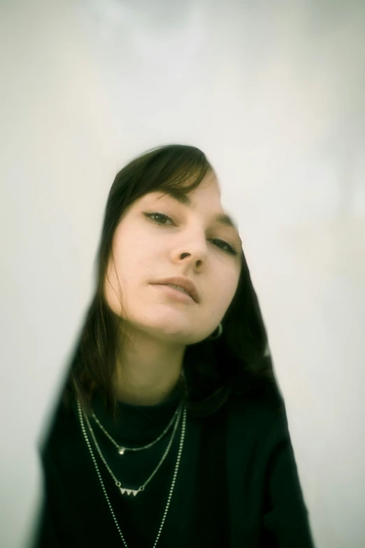 woman with black shirt and necklace standing near wall