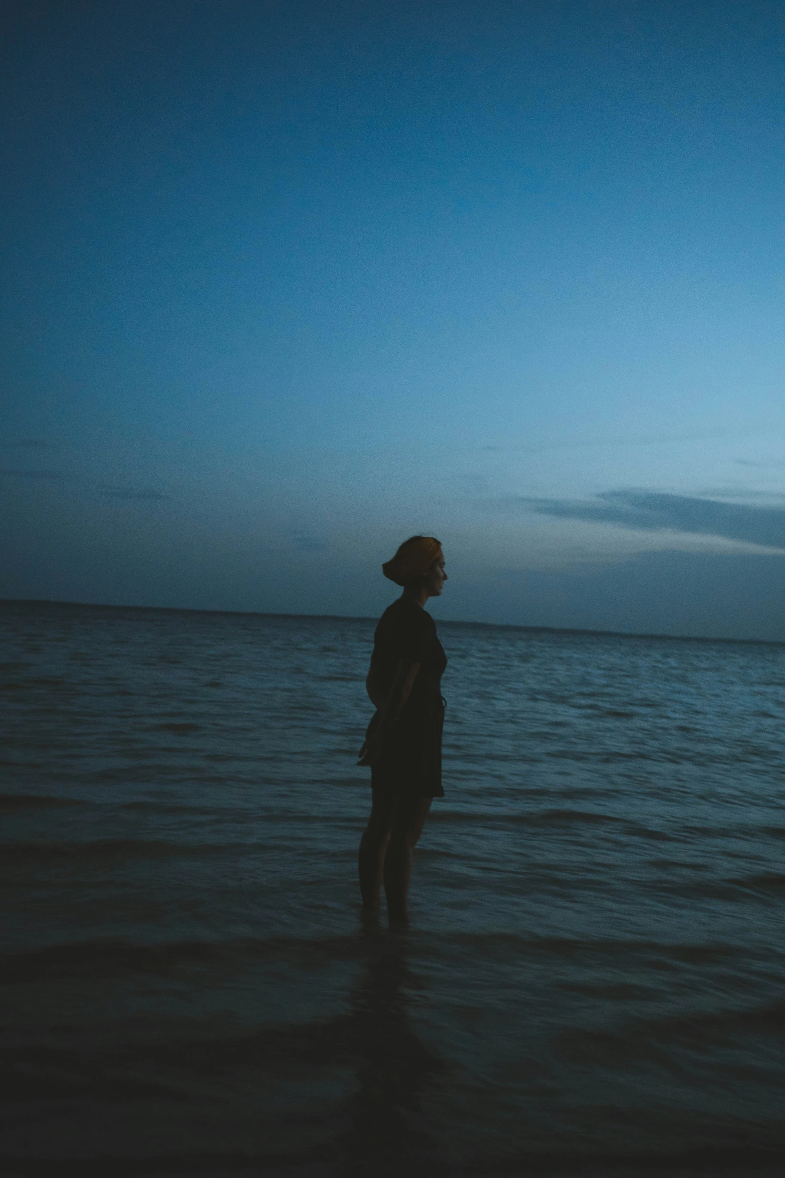 a woman standing on the beach at night