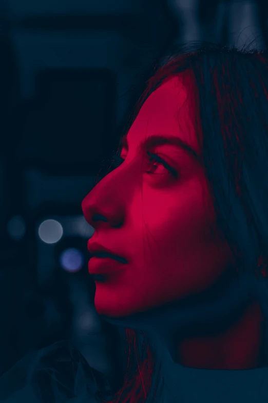 a woman staring ahead in the dark and red light
