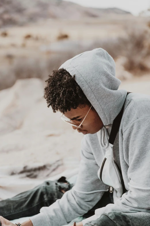 a guy in grey sweater and backpack checking his cellphone