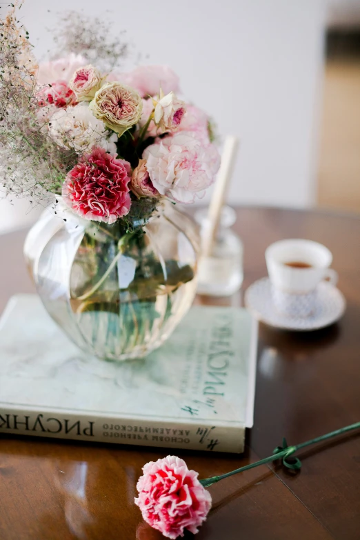 a table topped with vase filled with flowers on top of a book
