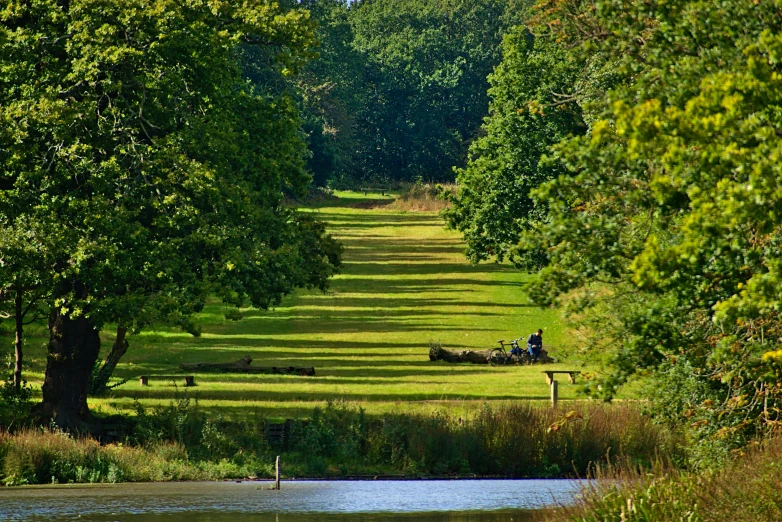 a group of people sitting on a bench next to a river