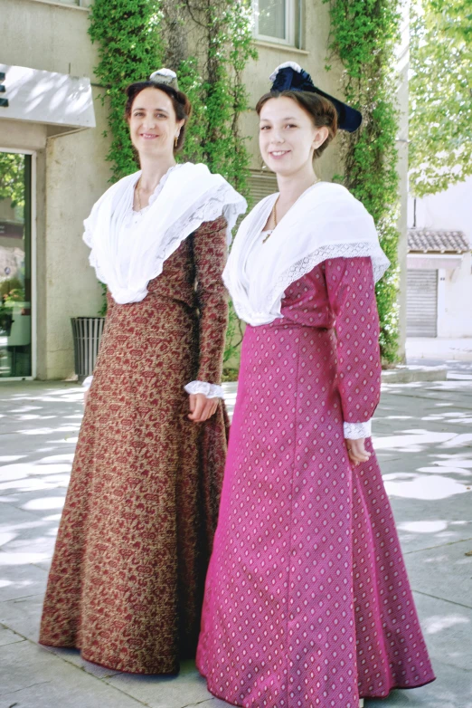 two women in dresses that have ruffles and a white collar