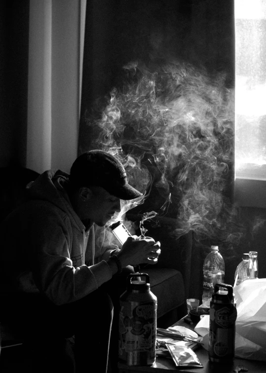 a person is sitting at a table looking down while smoke billows out