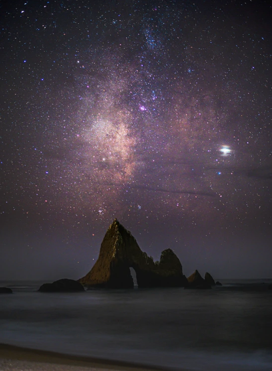 a mountain with stars on the sky and water