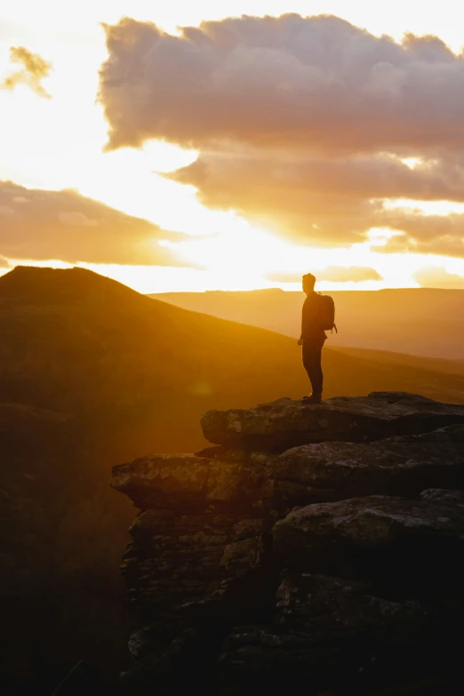 the person is standing on a cliff near mountains