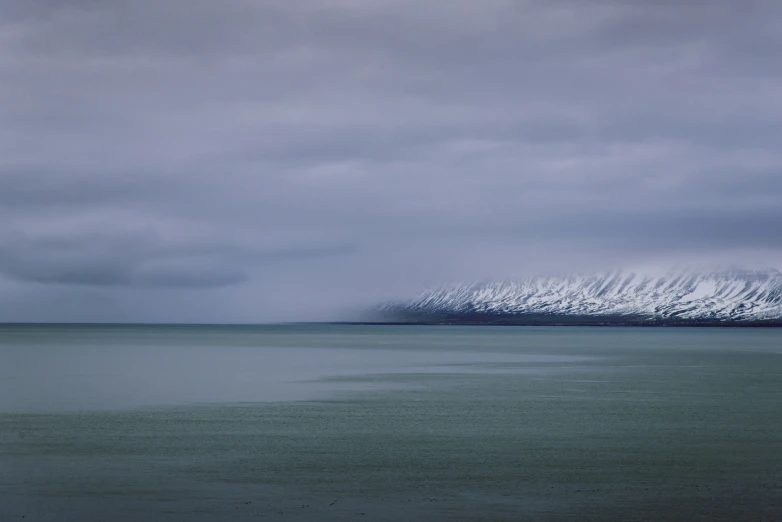 snowy mountains rise into the distance over calm water