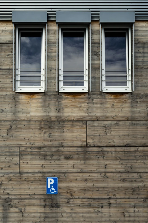 a parking sign attached to a wall with three windows