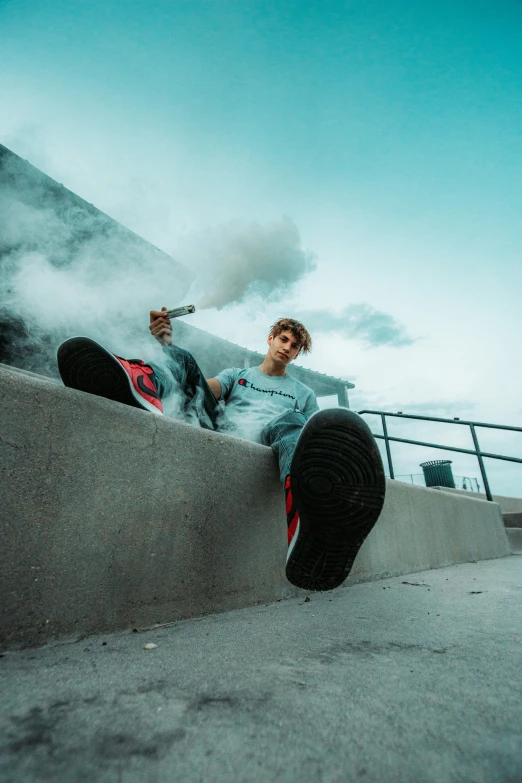 a young man is sitting down and smoking a cigarette