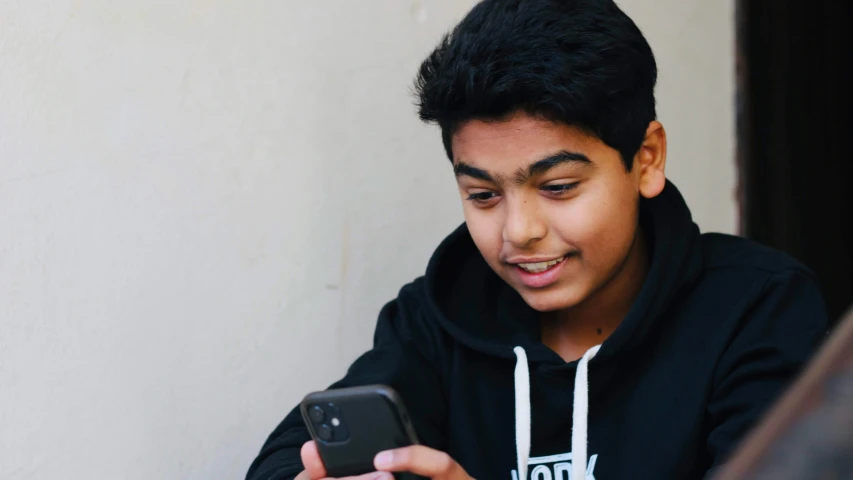 boy in black hoodie looking at phone screen