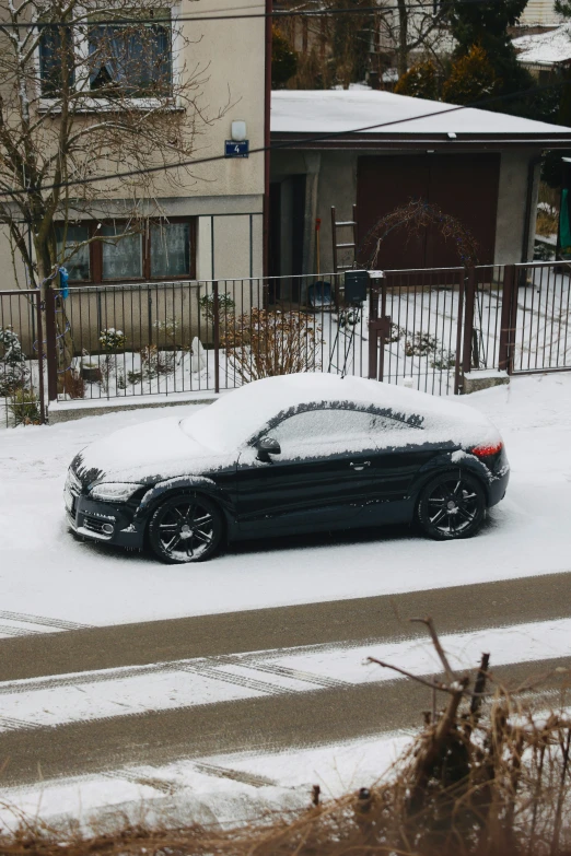 a car covered in snow parked on the side of the street