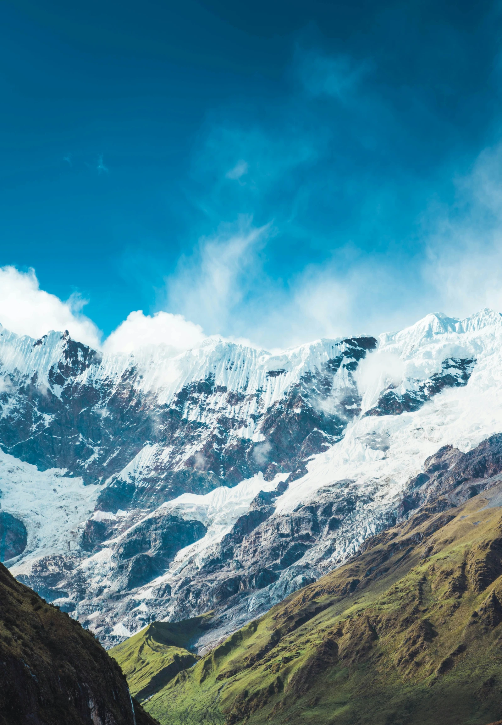 a mountain with snow capped mountains and grassy area below it