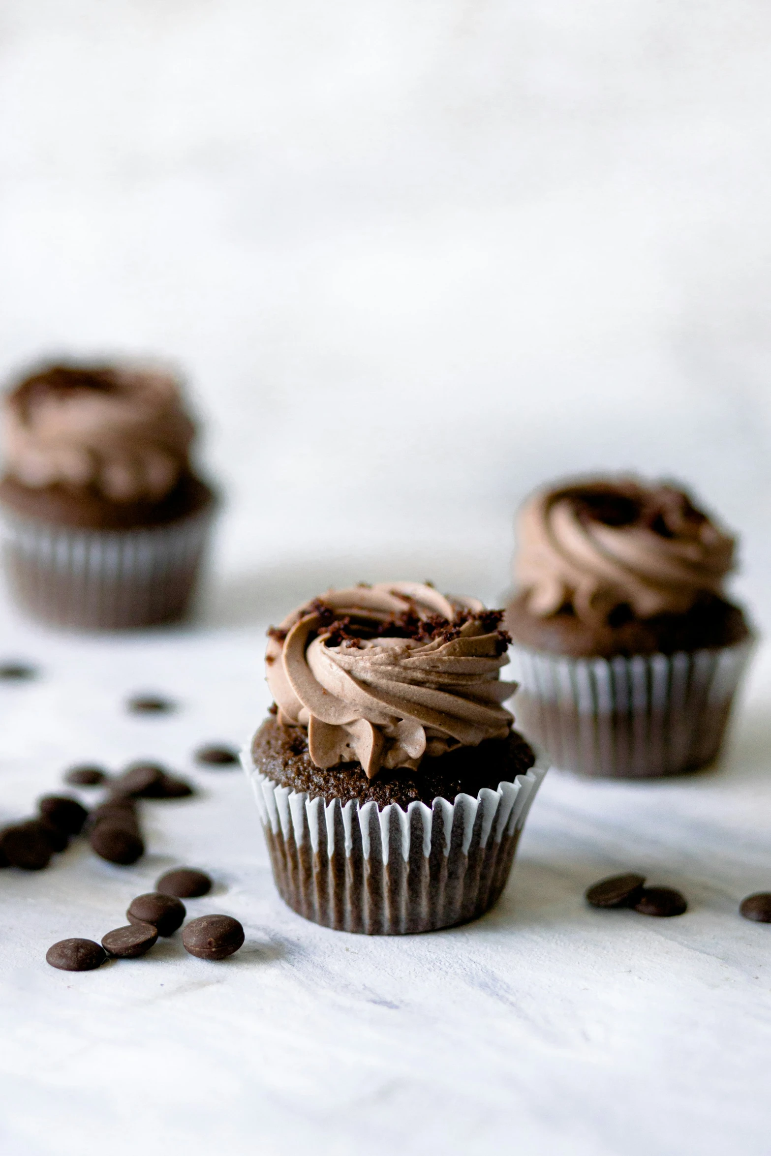 chocolate cupcakes frosted in chocolate chips on white cloth