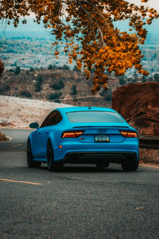 blue sedan is parked on the side of a road