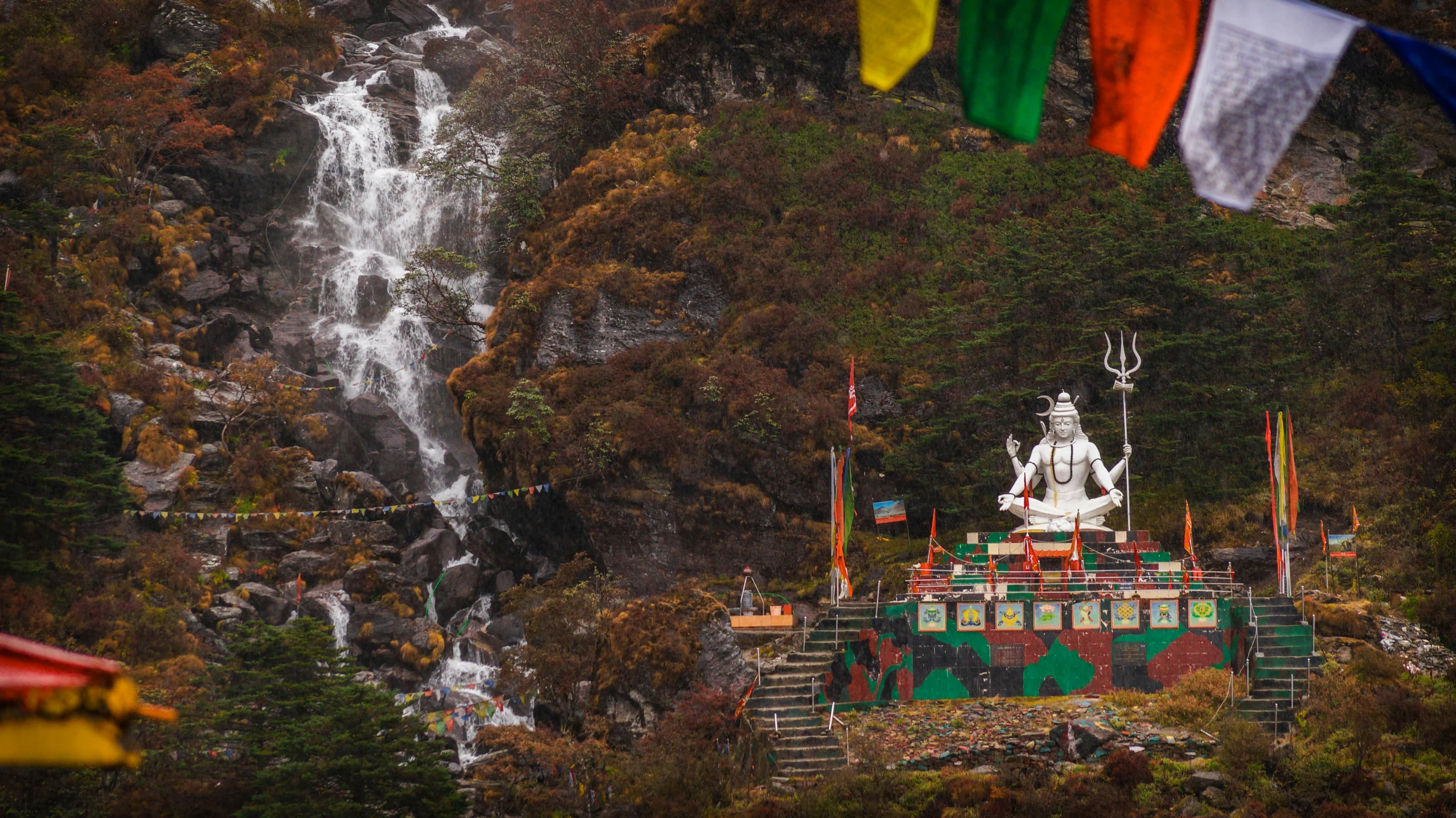 an ornate white and green building with lots of flags near a waterfall