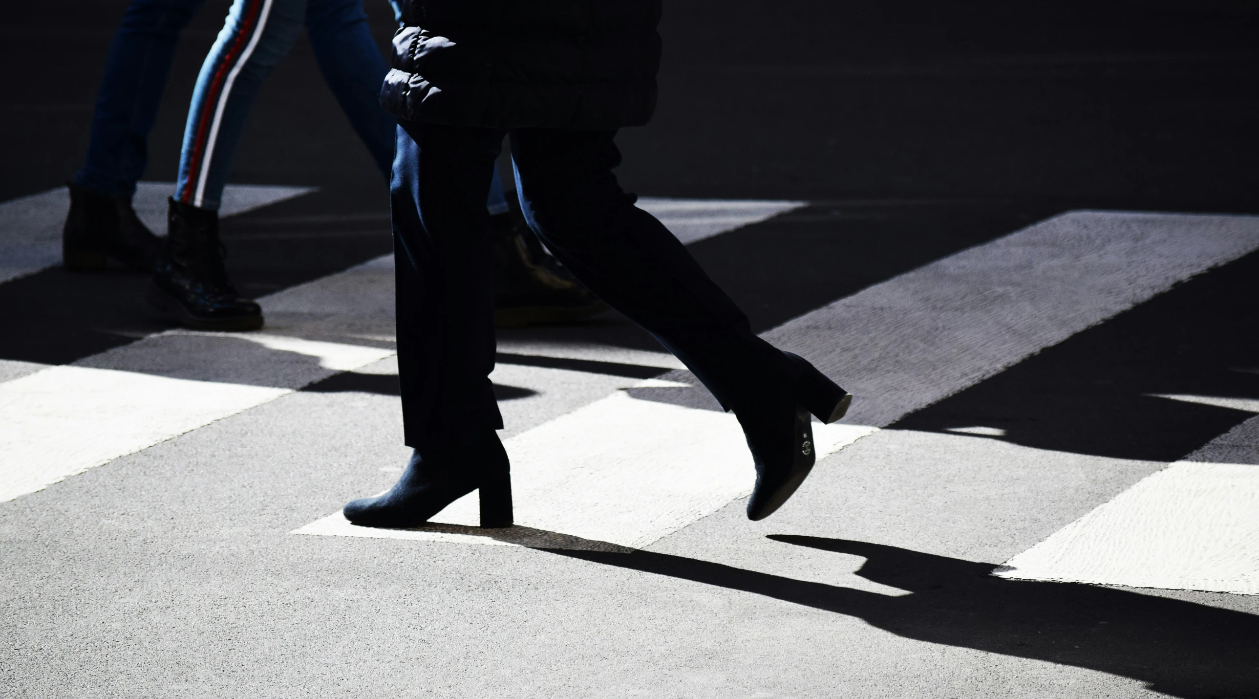 two people walking across a crosswalk in the day