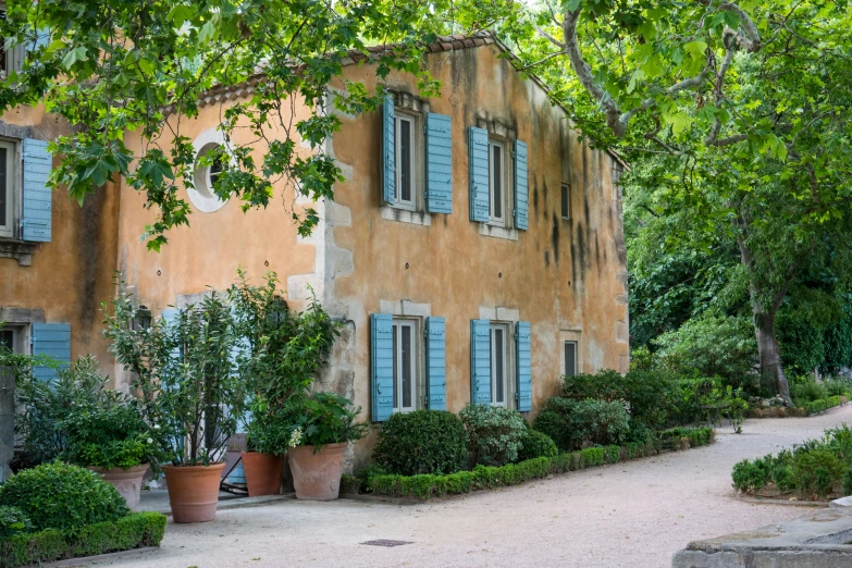 a large brown building with windows surrounded by potted trees