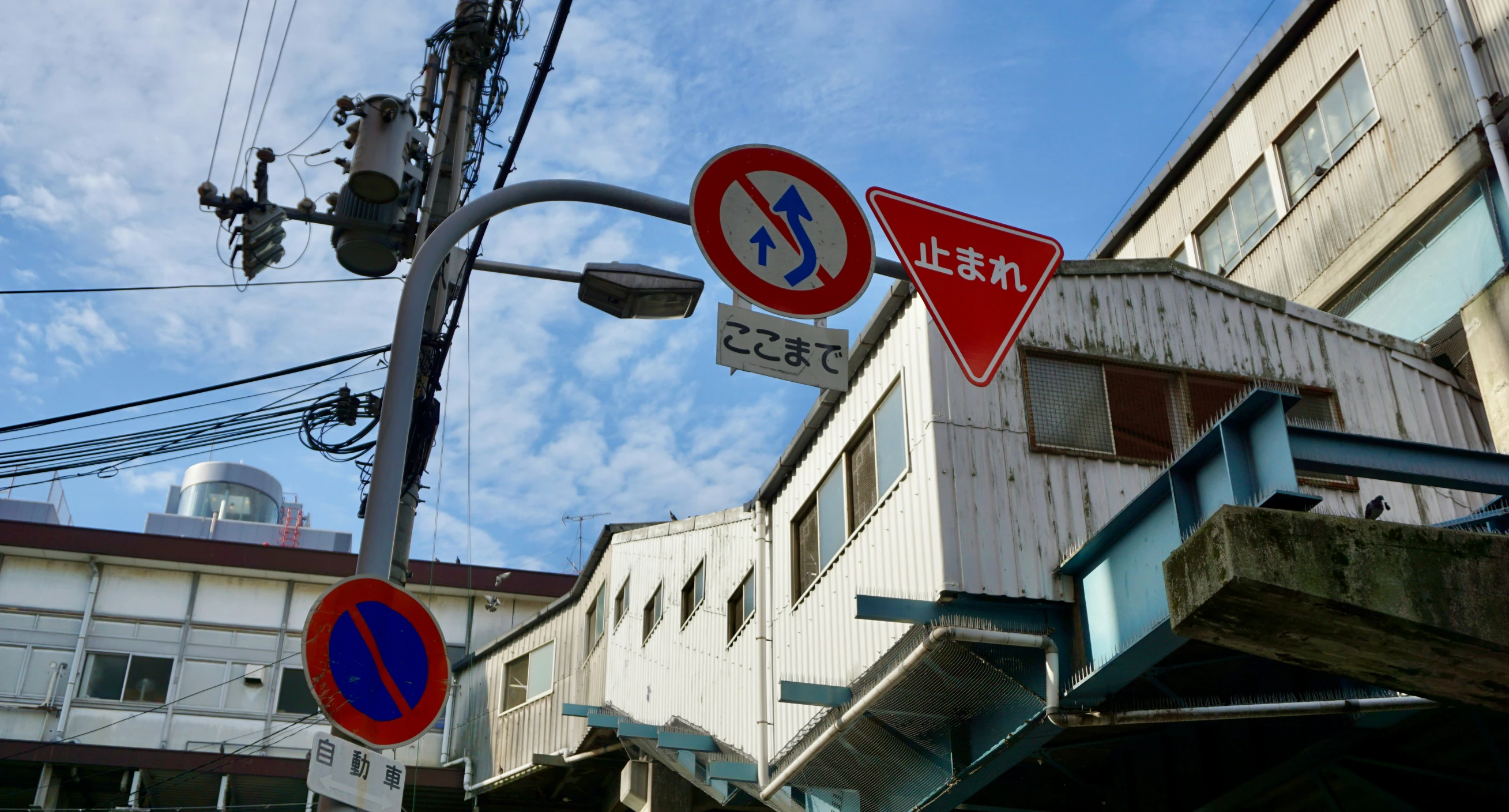 several street signs hanging near a high building