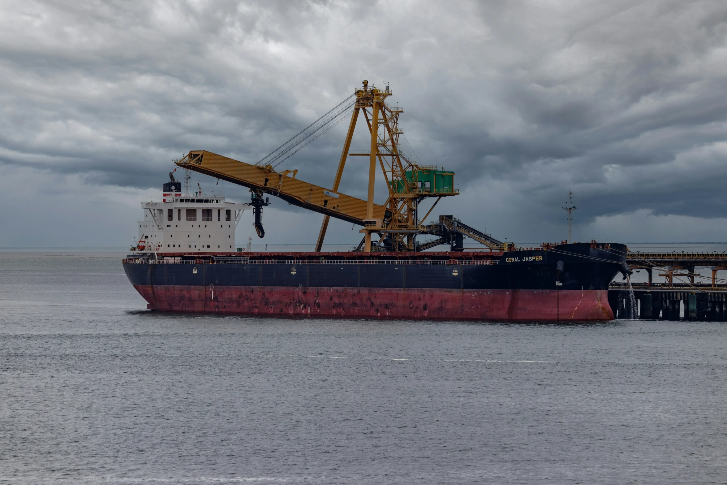 a crane loads cargo on to a large ship in a body of water