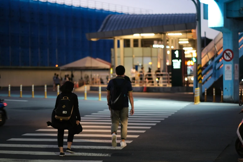 people walk across a crosswalk at dusk