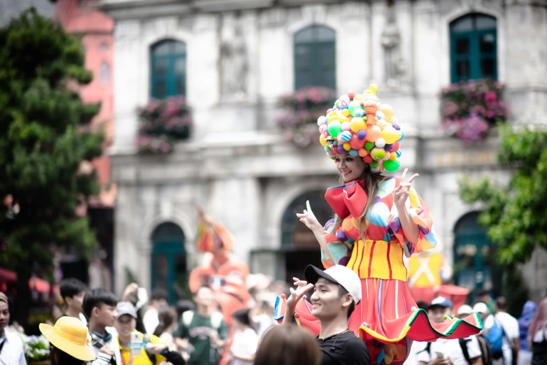 colorfully dressed woman in colorful parade dress dancing with others