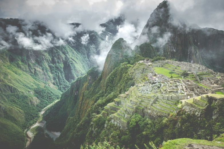 clouds are rolling over the mountains surrounding a village