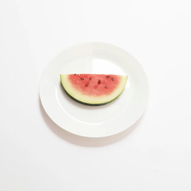 a piece of watermelon sits on a white plate