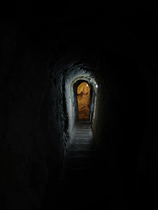 a tunnel is lit with a yellow light and some steps