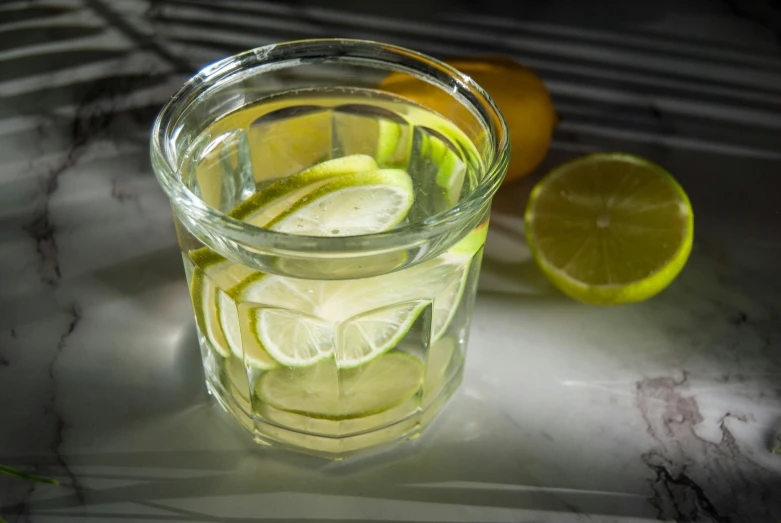 a glass cup filled with liquid with slices of lemon on the side