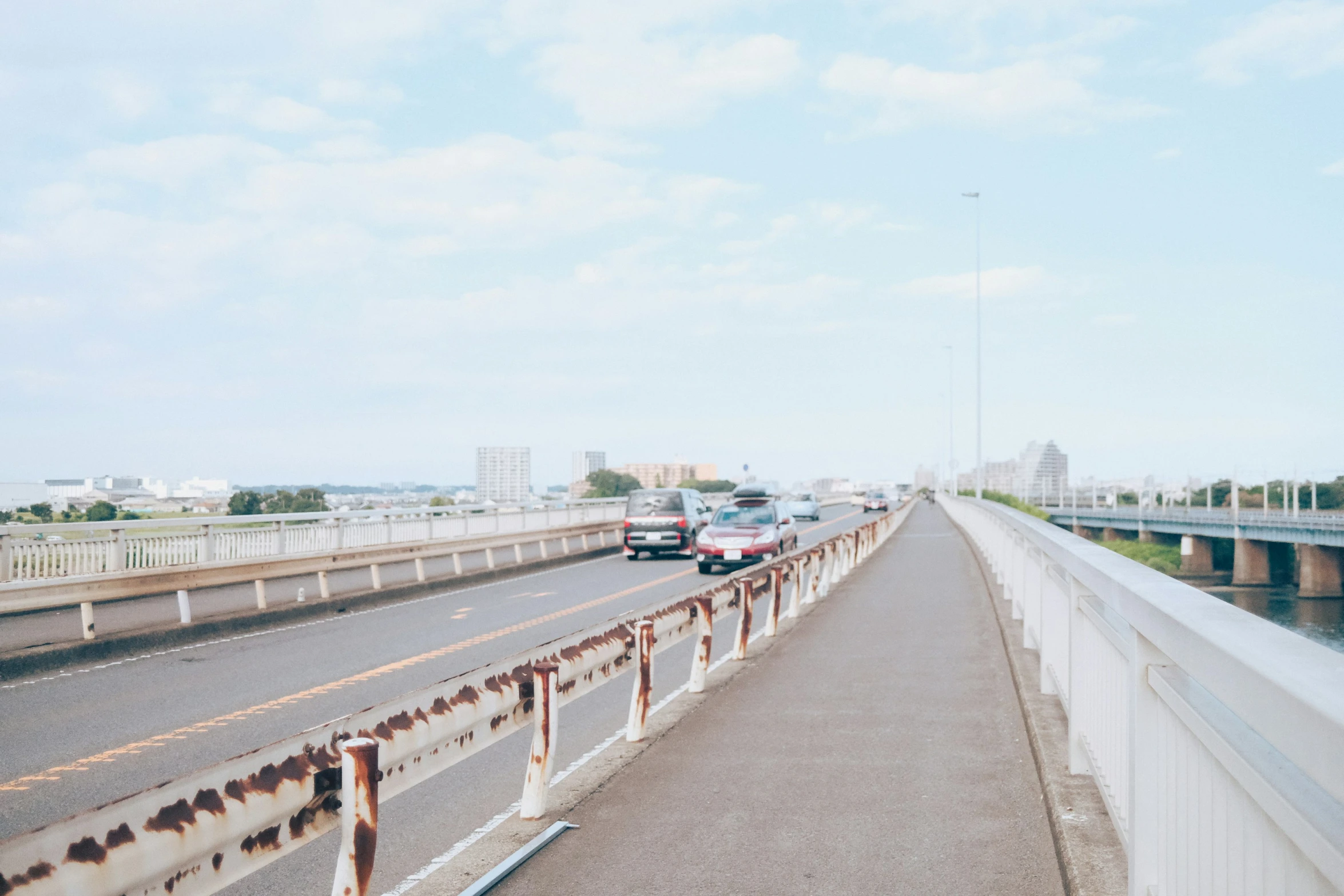 a highway is filled with cars and rusted steel rail railings