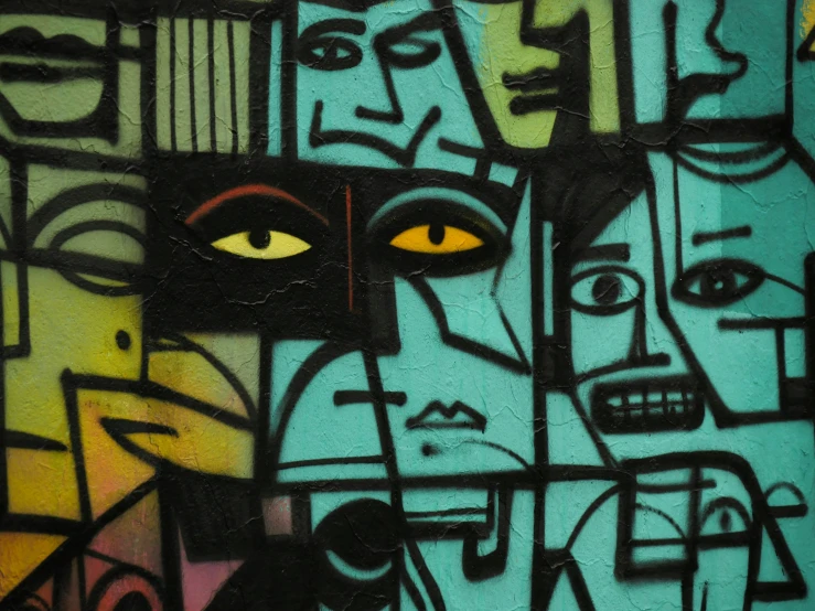 graffiti depicting multiple faces on a turquoise wall