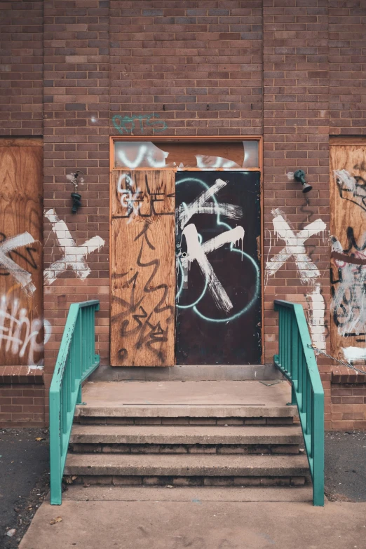 a stairway leading up to a brick wall covered in grafitti