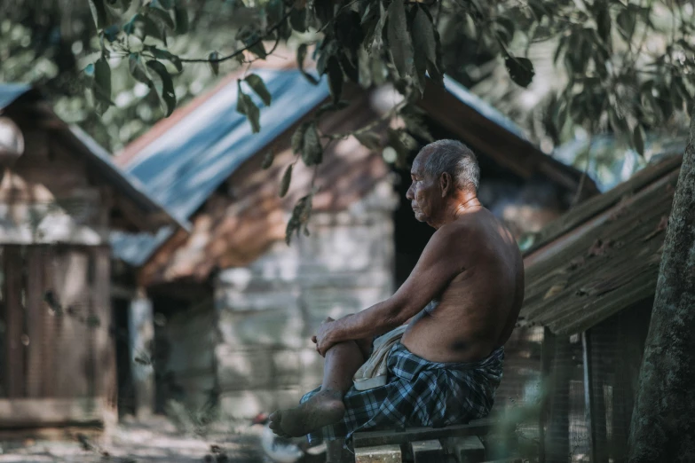 an older man sits on the steps next to a tree