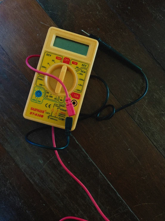 a yellow electronic meter with some wires laying on top