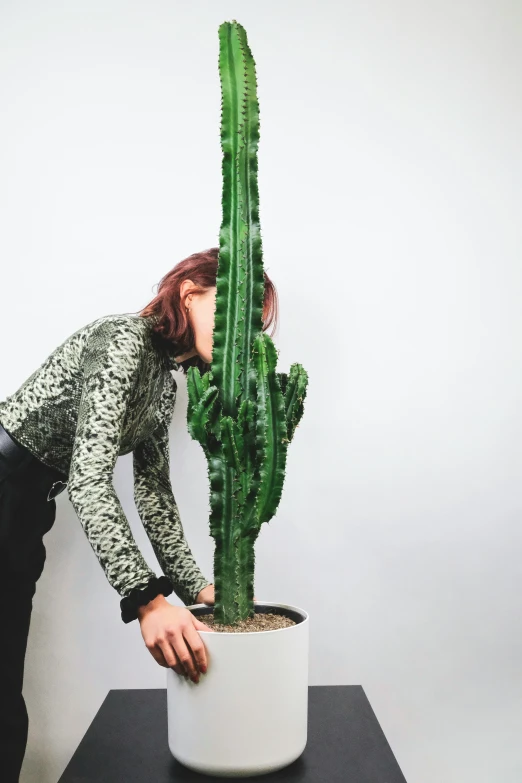 a woman bending down next to a cactus