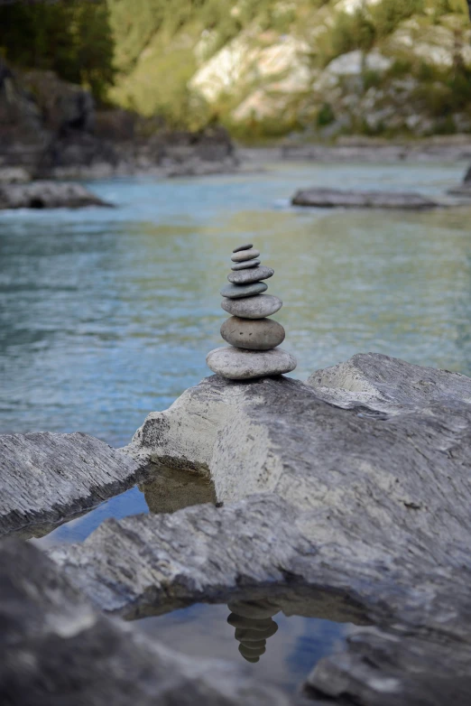 a stack of rocks sitting on top of a rock near water