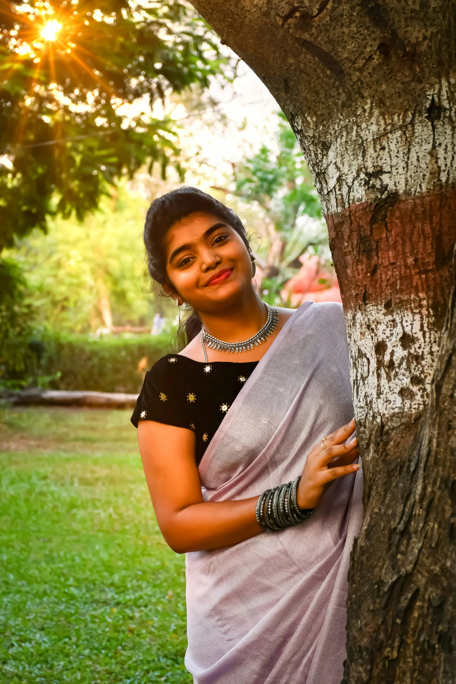 a woman is smiling while standing by a tree